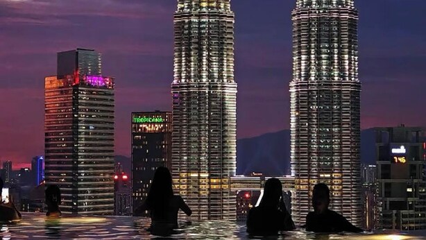 Deux gratte-ciel illuminés, avec une étendue d'eau au premier plan.
