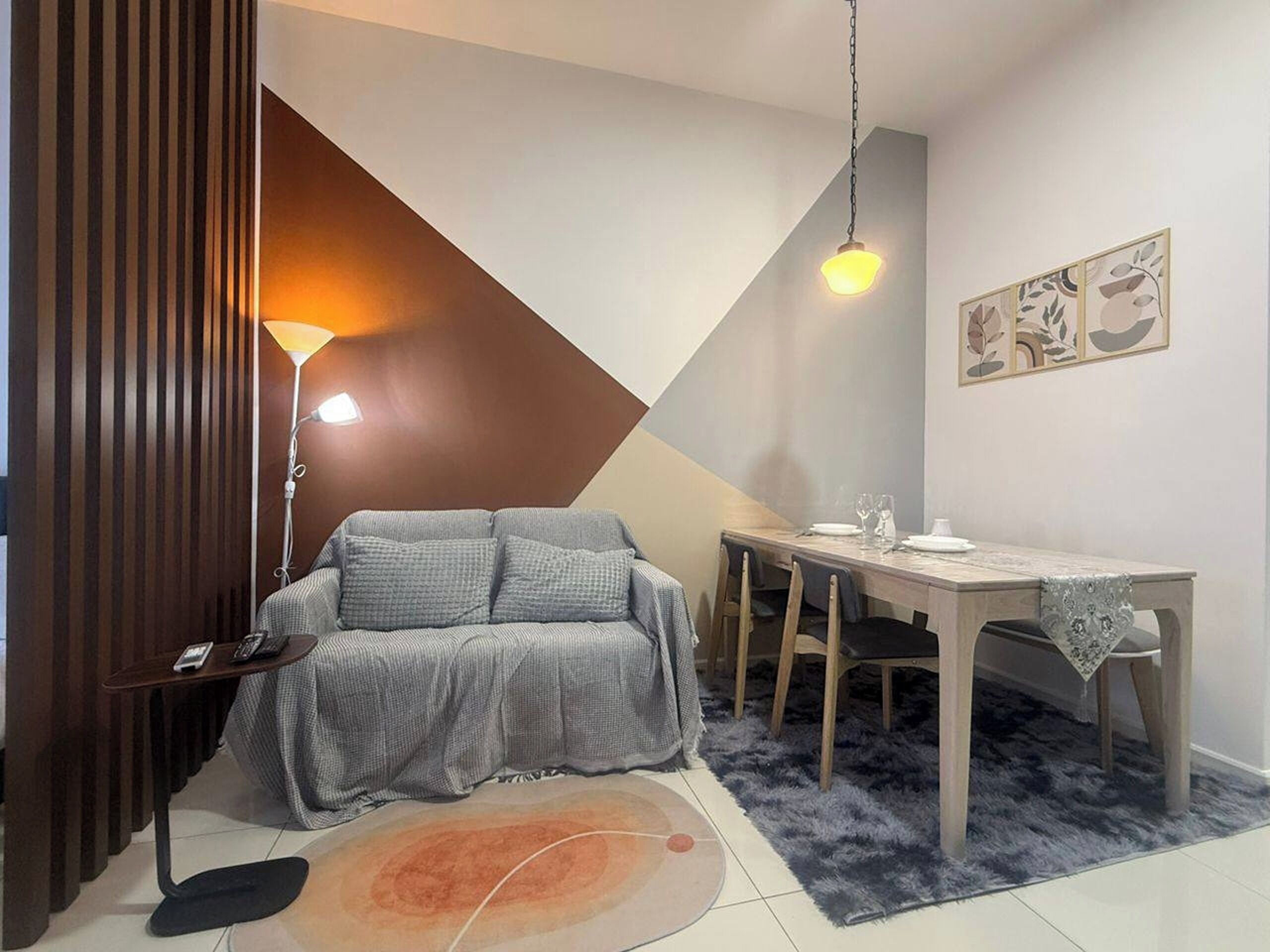 Una sala moderna con un sofá, una mesa de comedor y una lámpara.