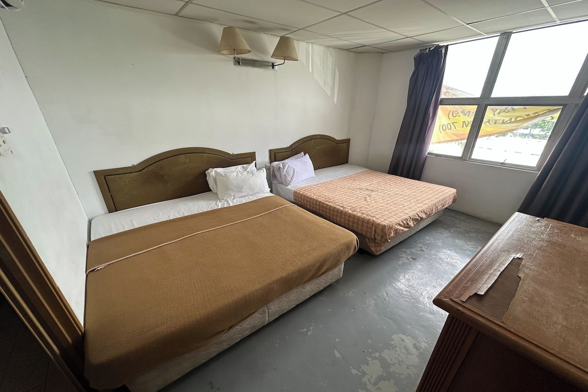 Una habitación de hotel con dos camas, una mesita y una ventana con cortinas.