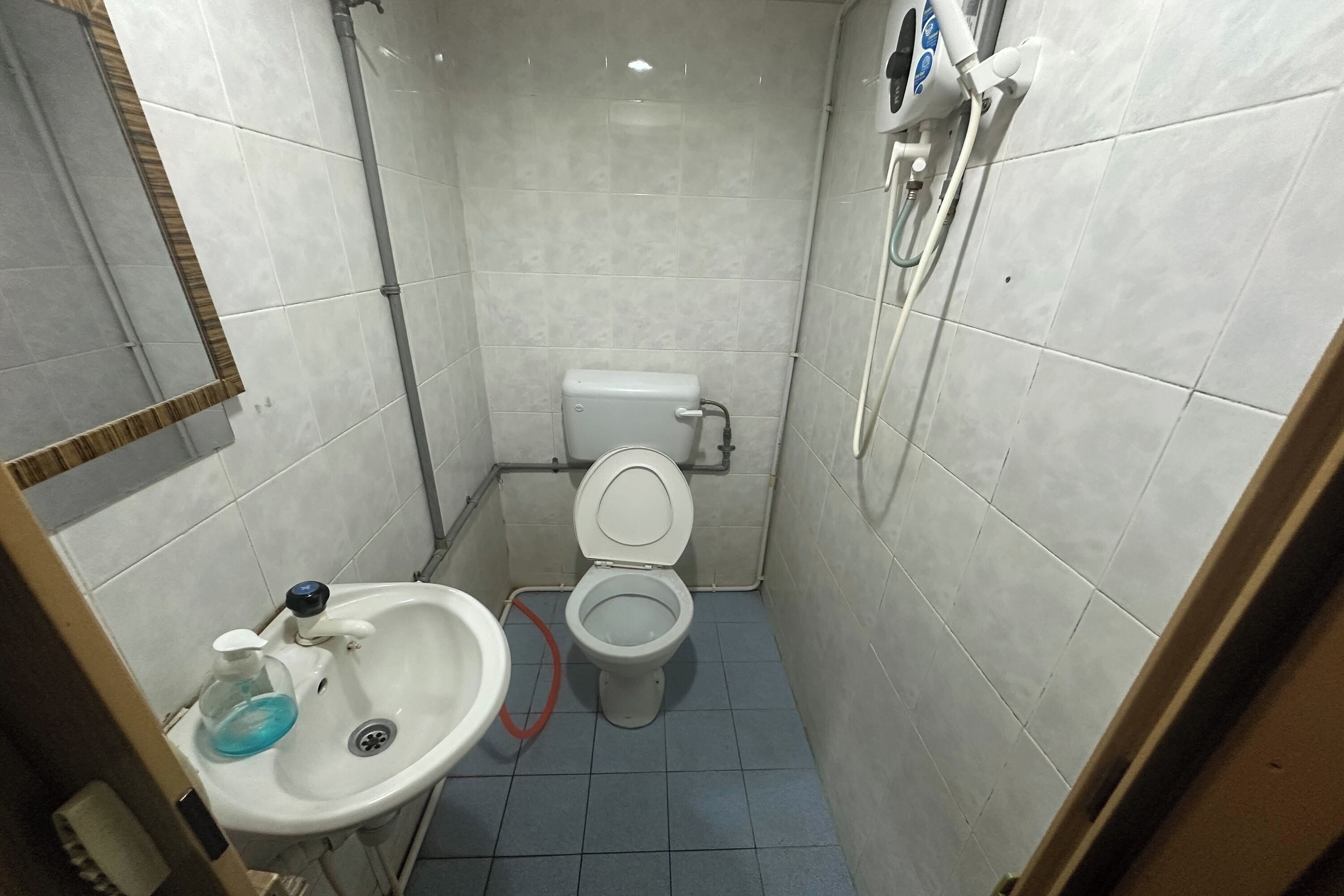 Un baño pequeño con azulejos, inodoro, lavamanos y ducha.