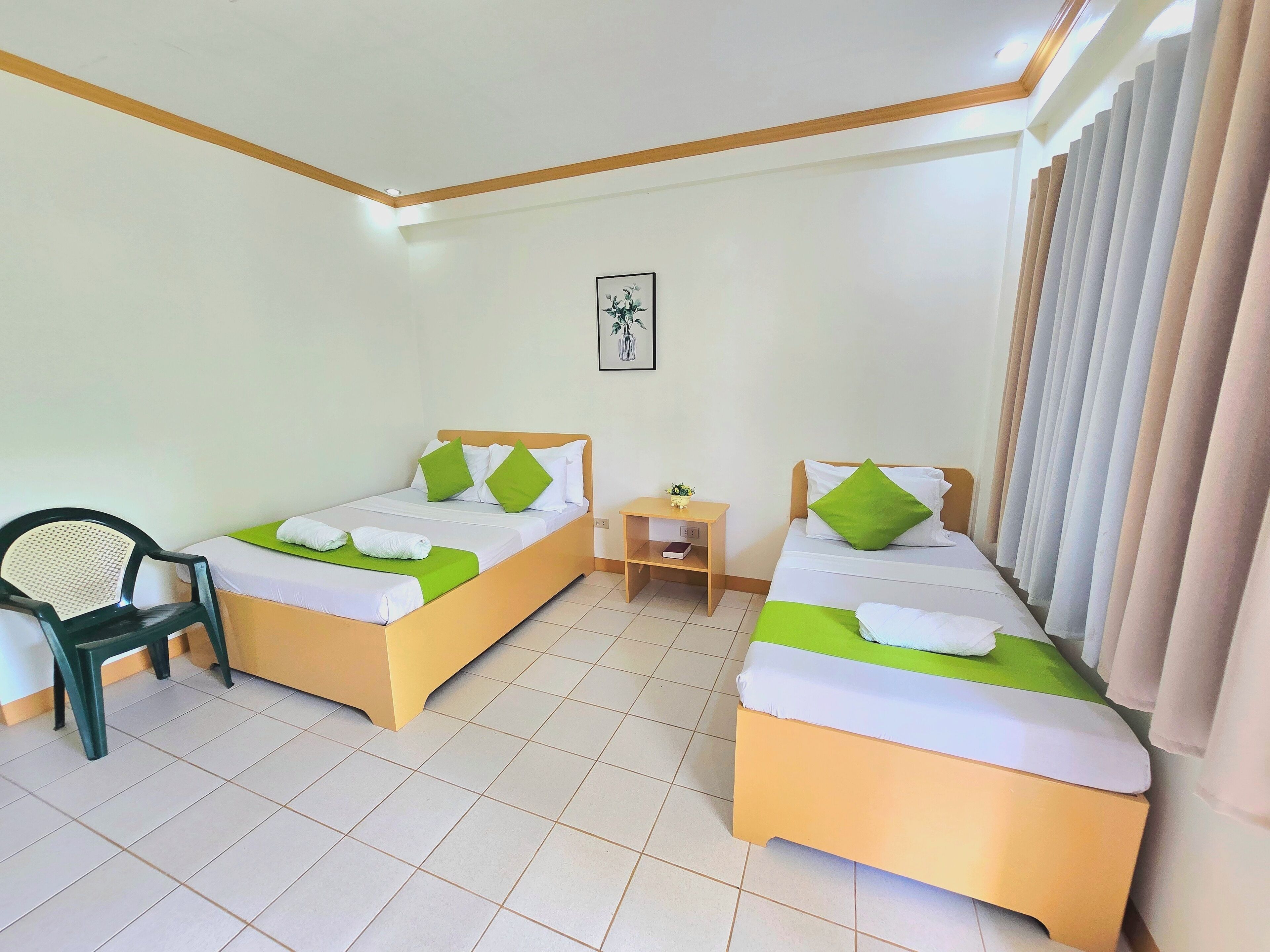 Habitació d'hotel amb dos llits, una cadira, una taula petita i un quadre a la paret.