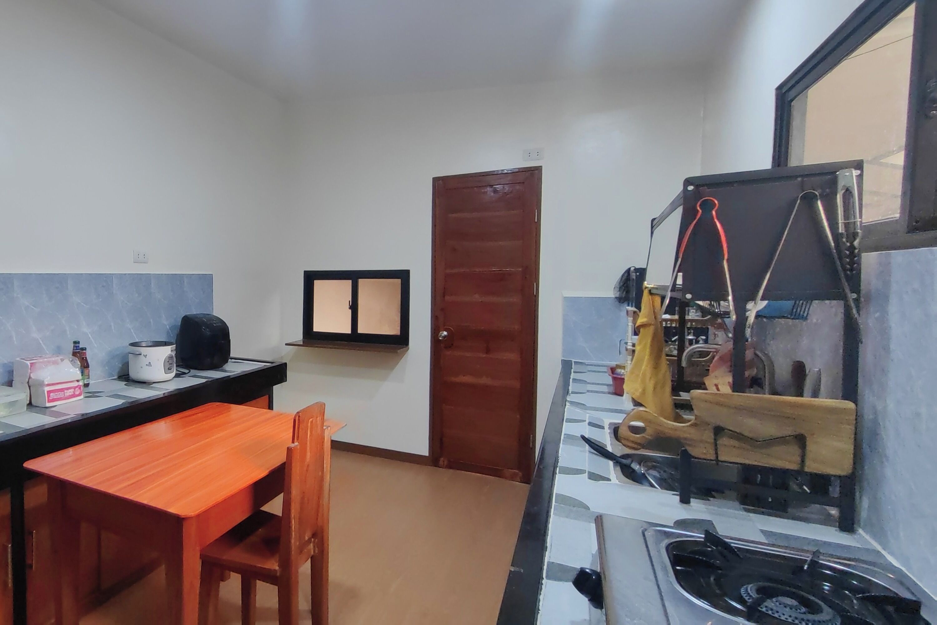 A compact kitchen with a gas stove, a small table, and a chair.