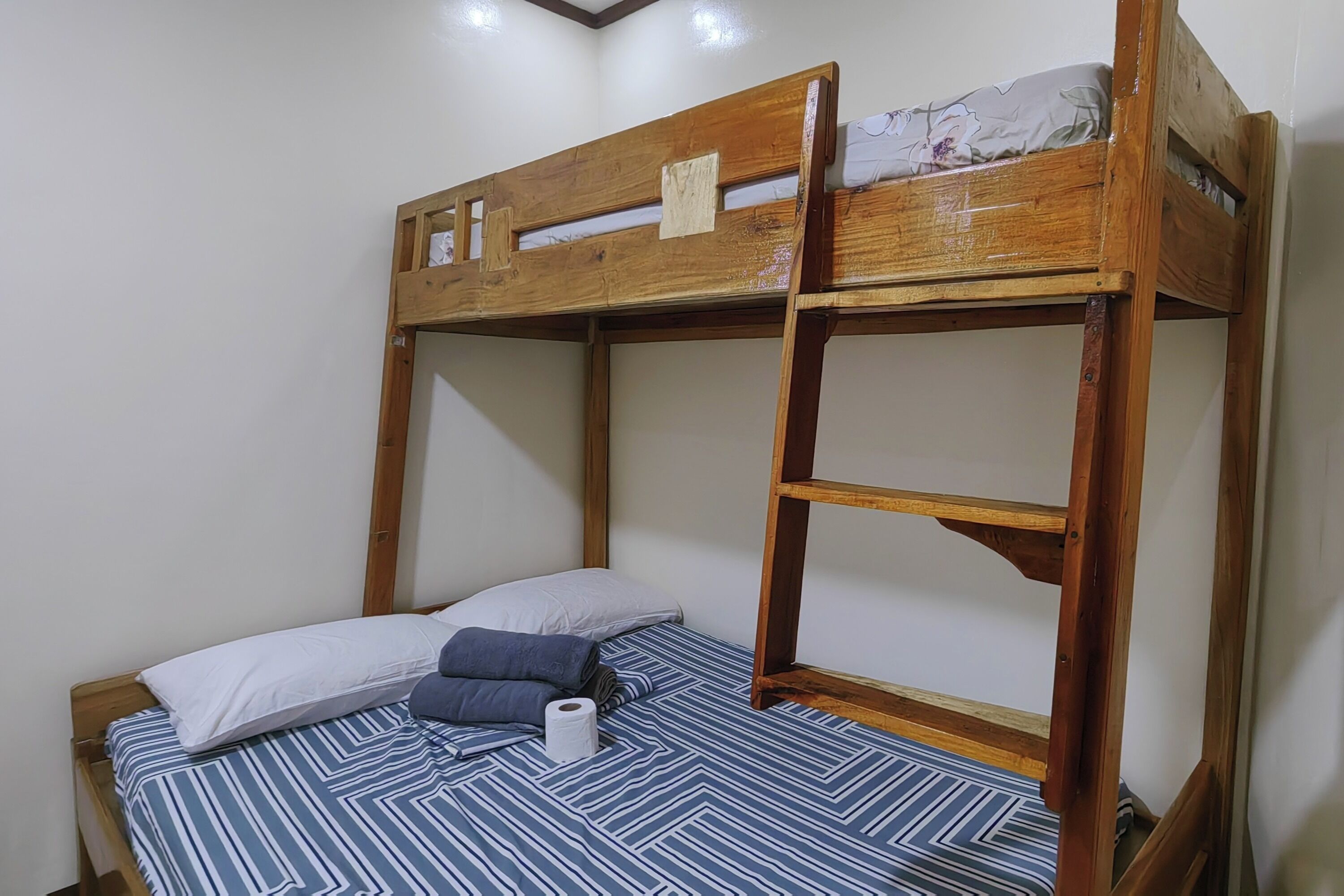 A bunk bed with a wooden frame, a striped bedspread, and pillows.