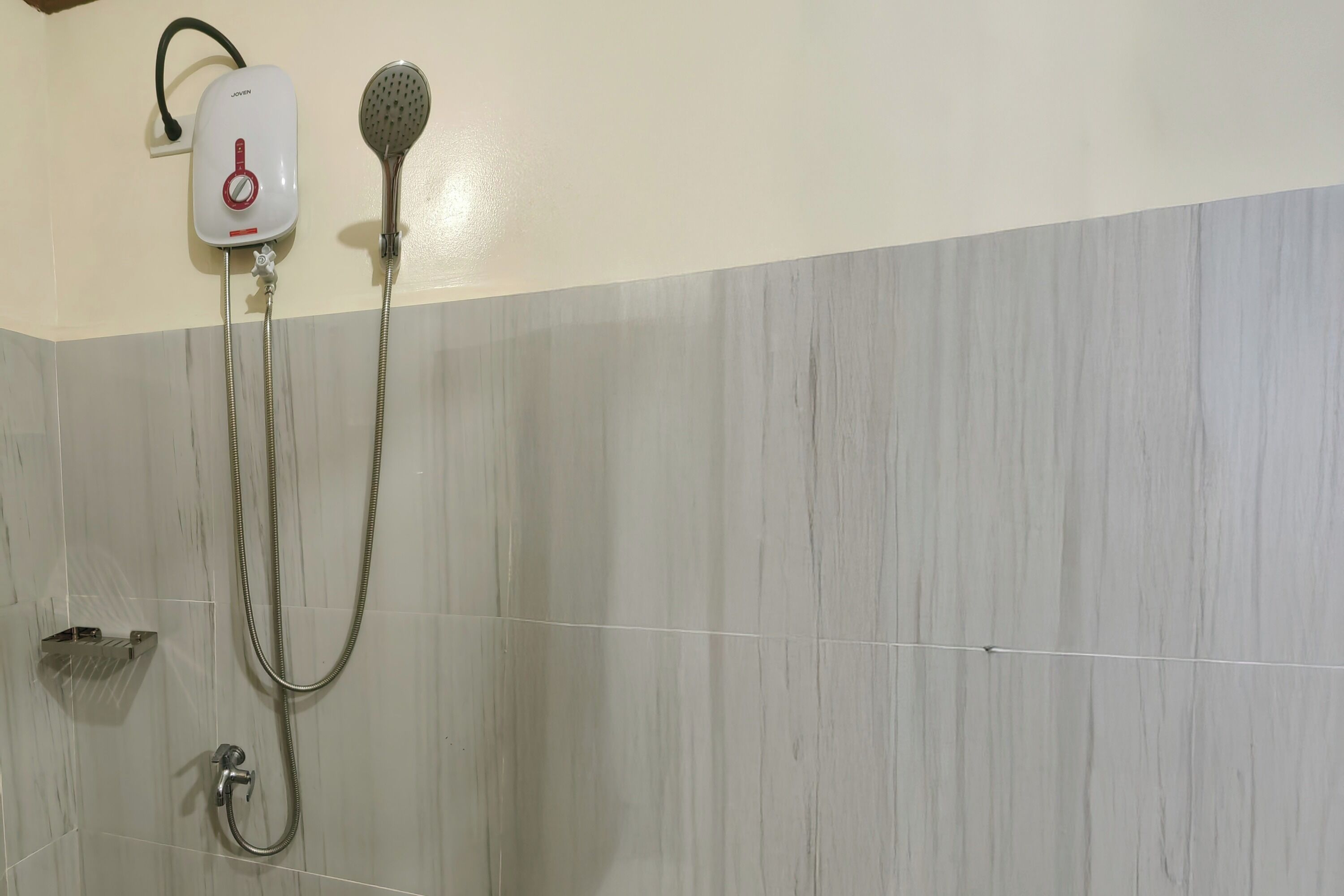 A shower with a handheld showerhead and a wall-mounted control panel.