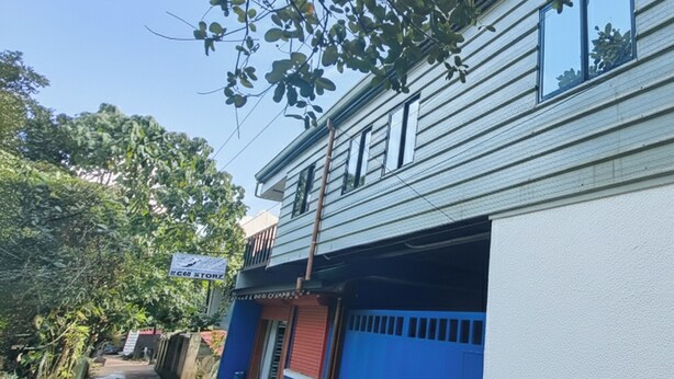 A narrow alley with a building on the right. The building has a blue door and a sign above it. - Summer Wind Pension House El Nido (El Nido)