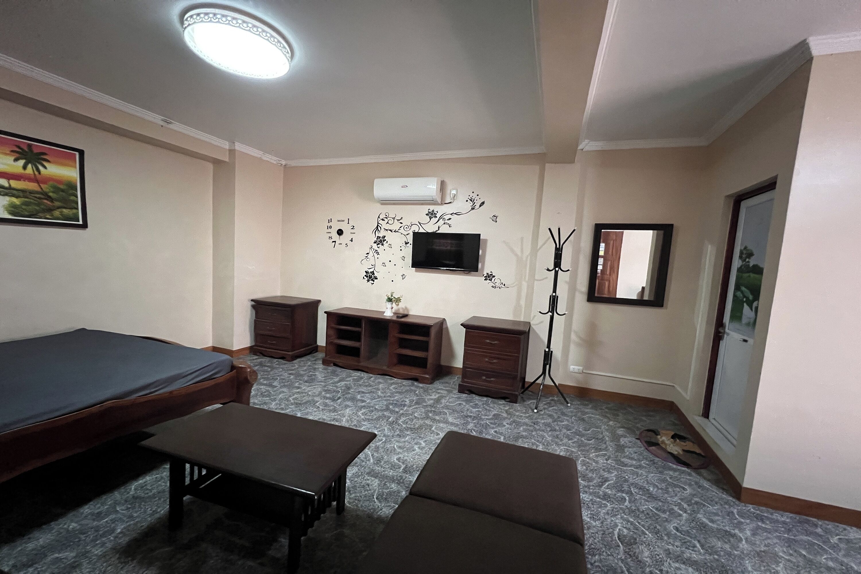 A room with a bed, a small table, a TV, and a decorative wall.