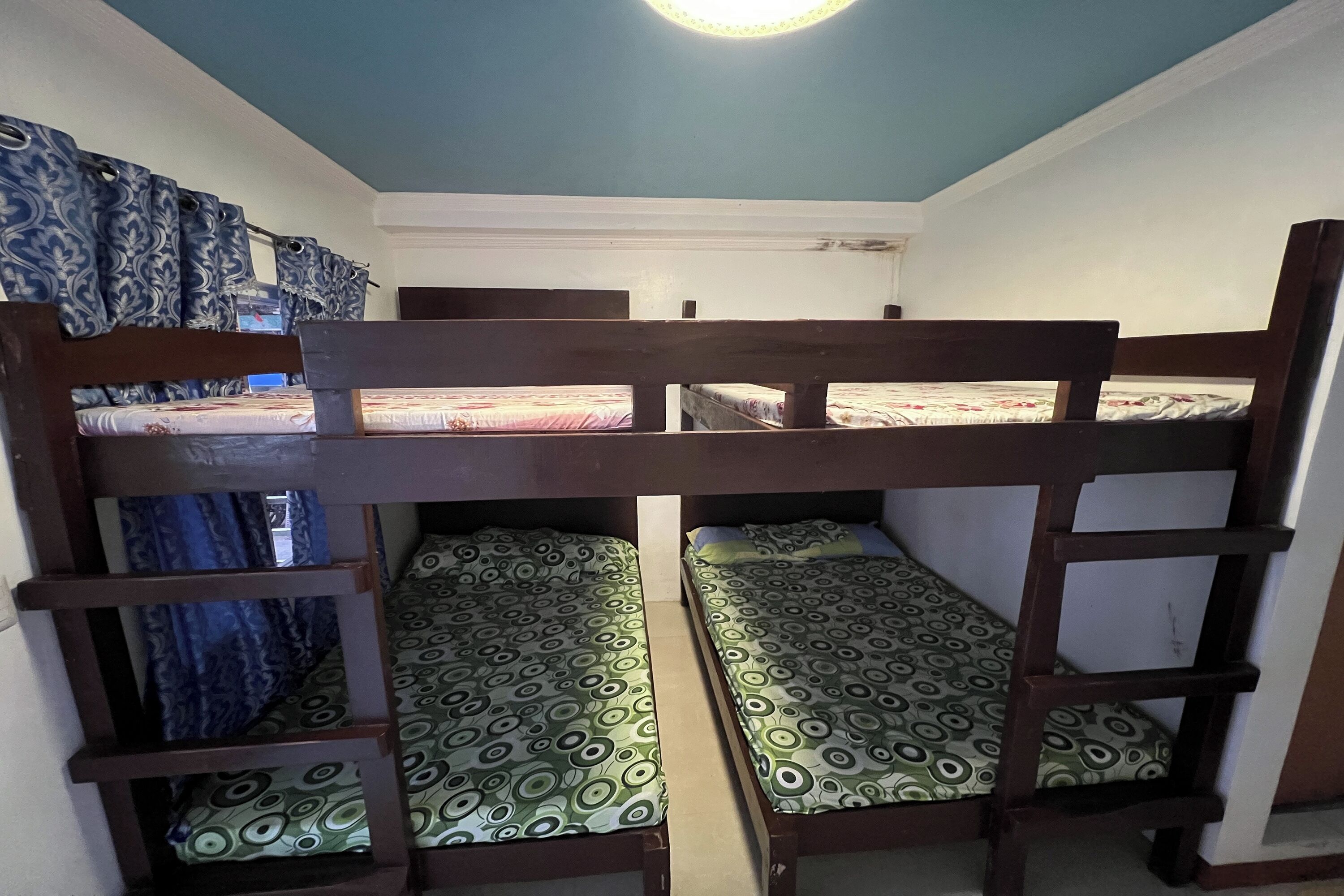 Une chambre avec un lit superposé, dotée de draps et de rideaux à motifs.