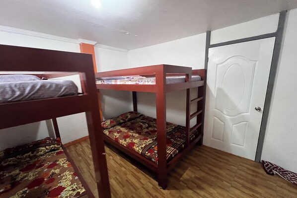 A room with bunk beds, a wooden floor, and a white door. - Kakay Beach Resort (San Narciso)
