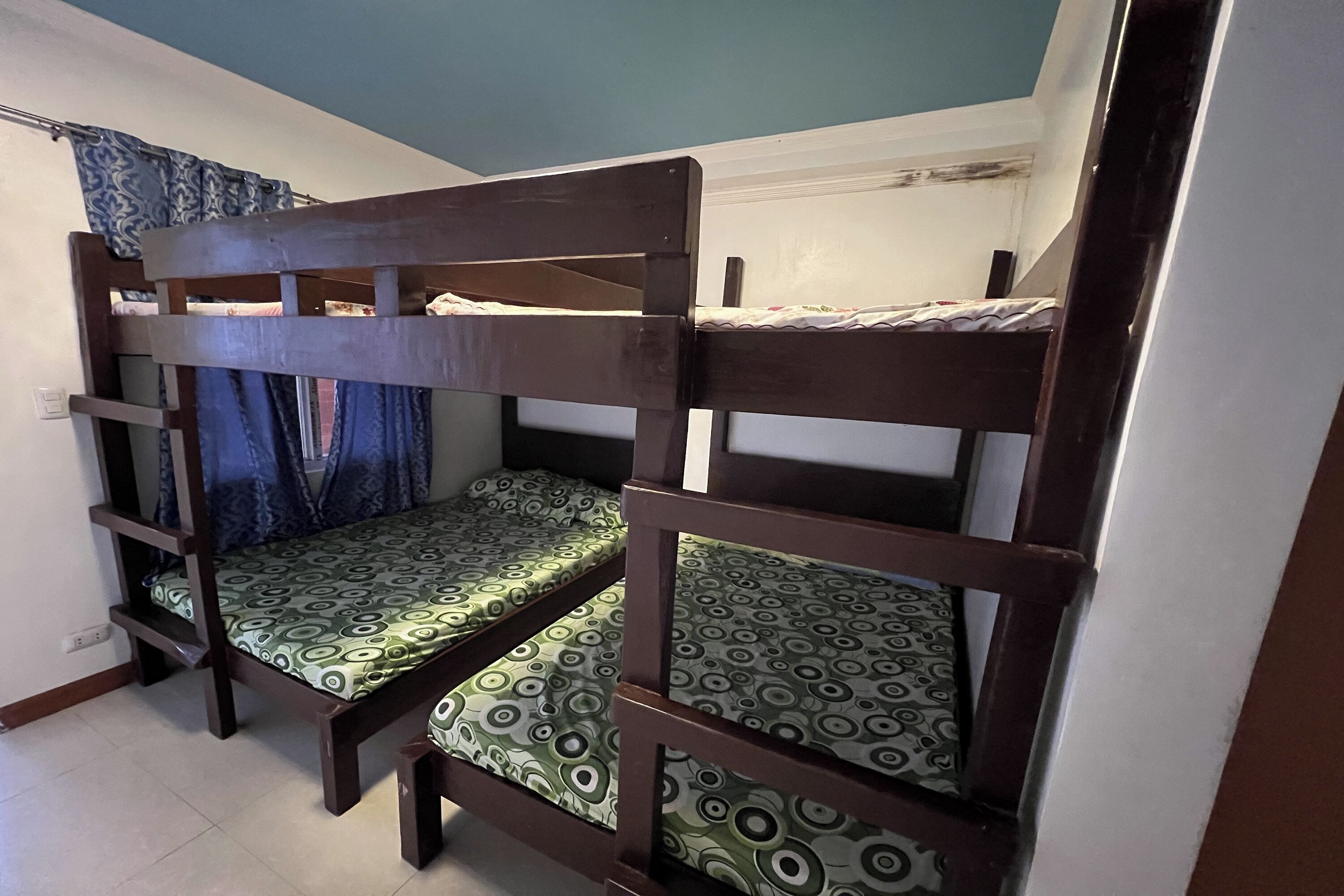 A bunk bed with a patterned mattress, a curtain, and a tiled floor.