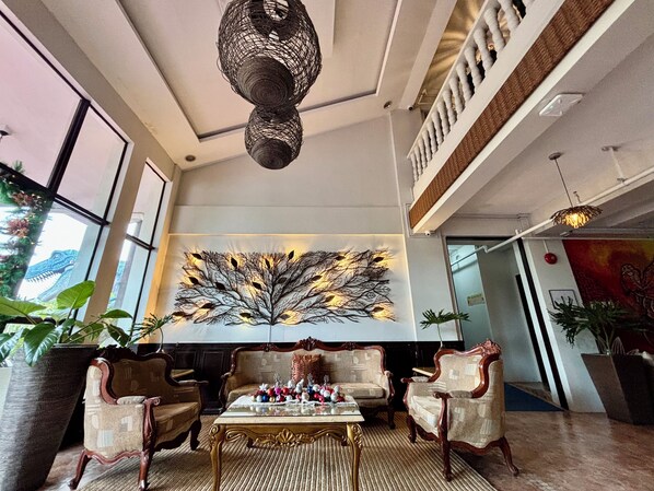 A lobby with a large wall art piece, wooden furniture, and a ceiling light fixture.