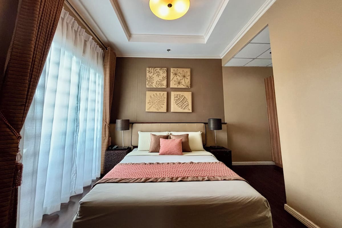 A hotel room with a large bed, a ceiling light, and wall art.