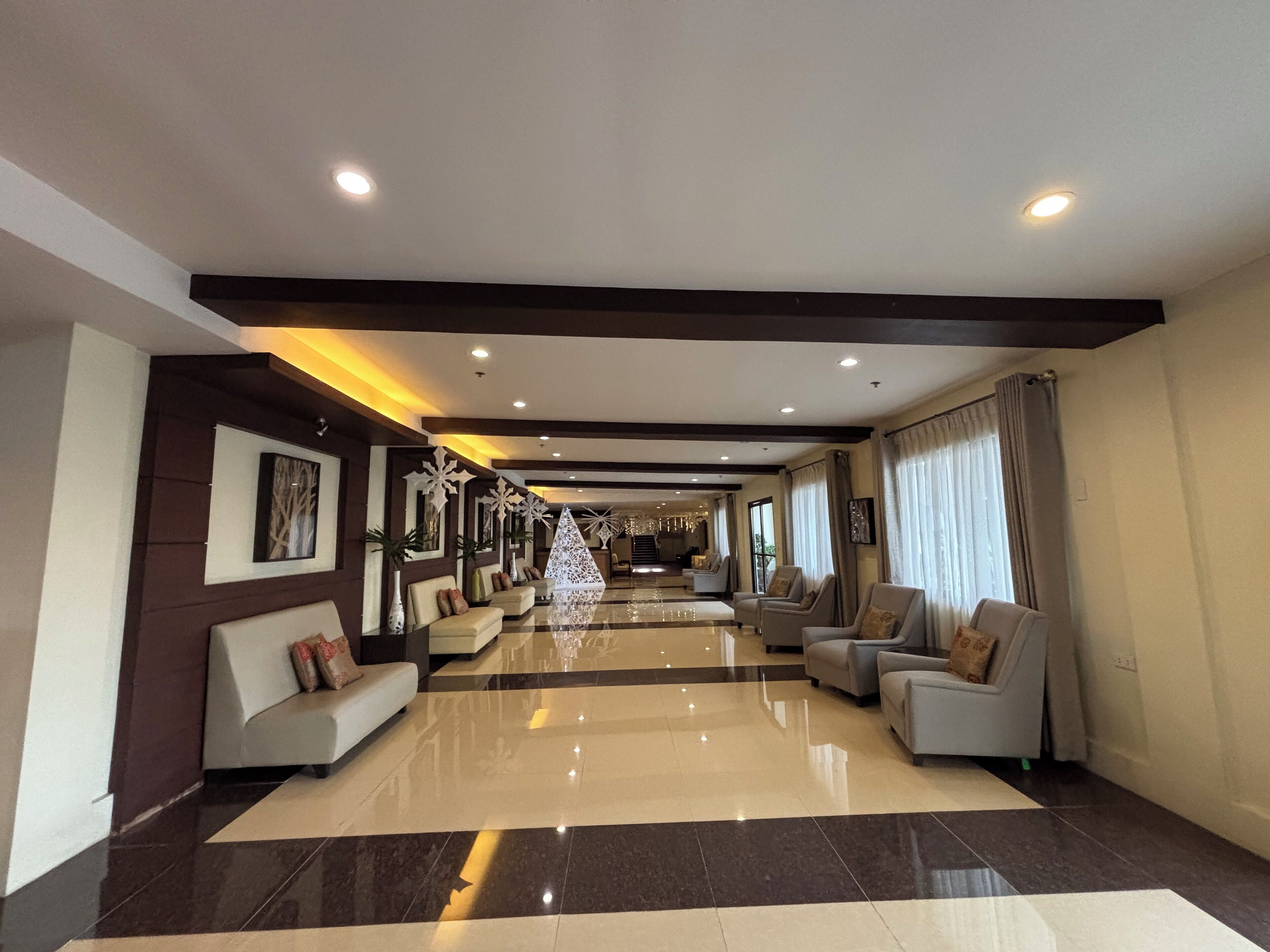 A spacious lobby with a polished floor, seating areas, and a staircase leading to upper floors.