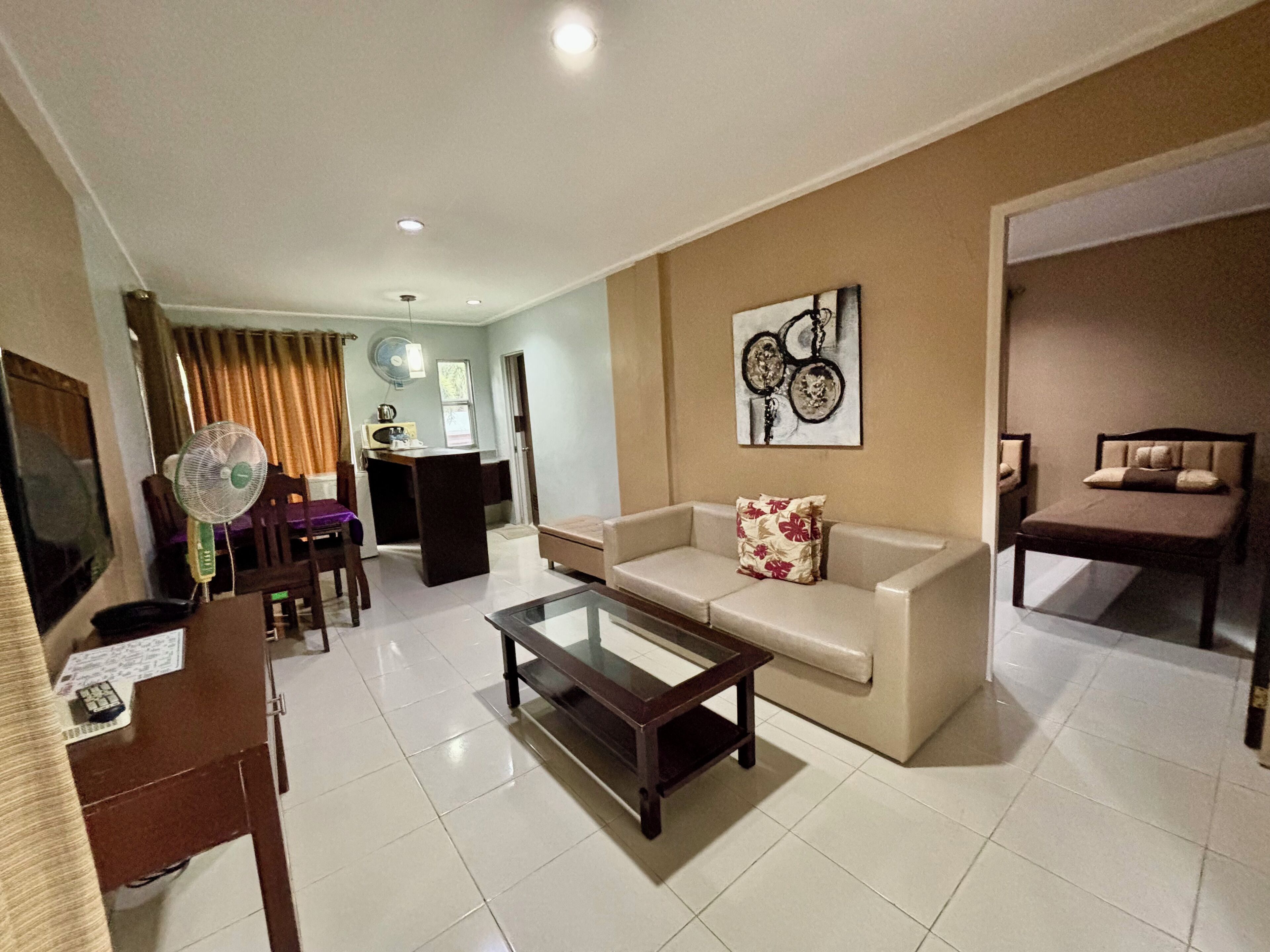 A living room with a sofa, coffee table, and a TV. There is a dining area with a table and chairs.