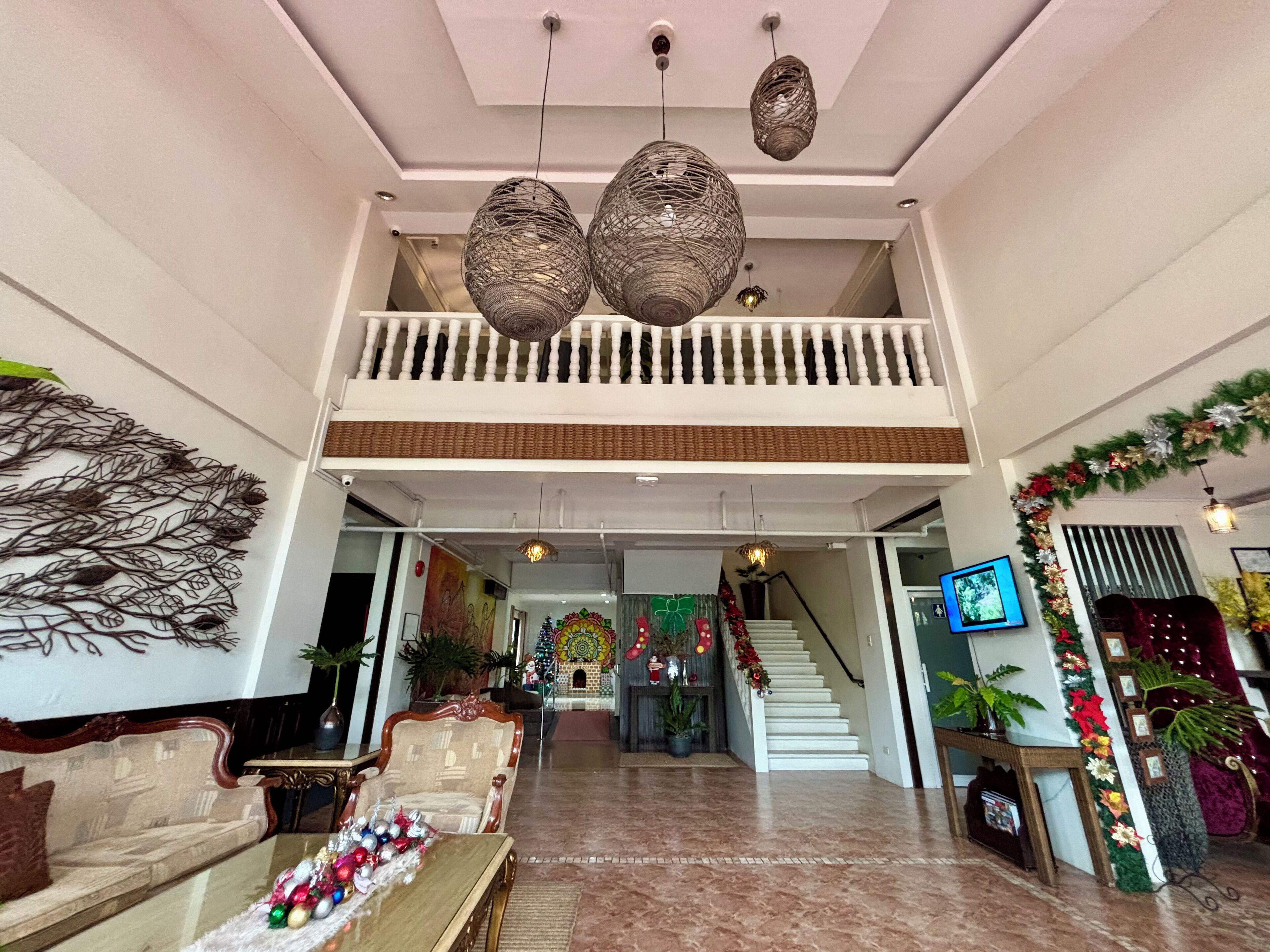 A spacious lobby with a high ceiling, a balcony, and a staircase leading to a lower level.