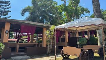 A building with a covered outdoor seating area and a cart.
