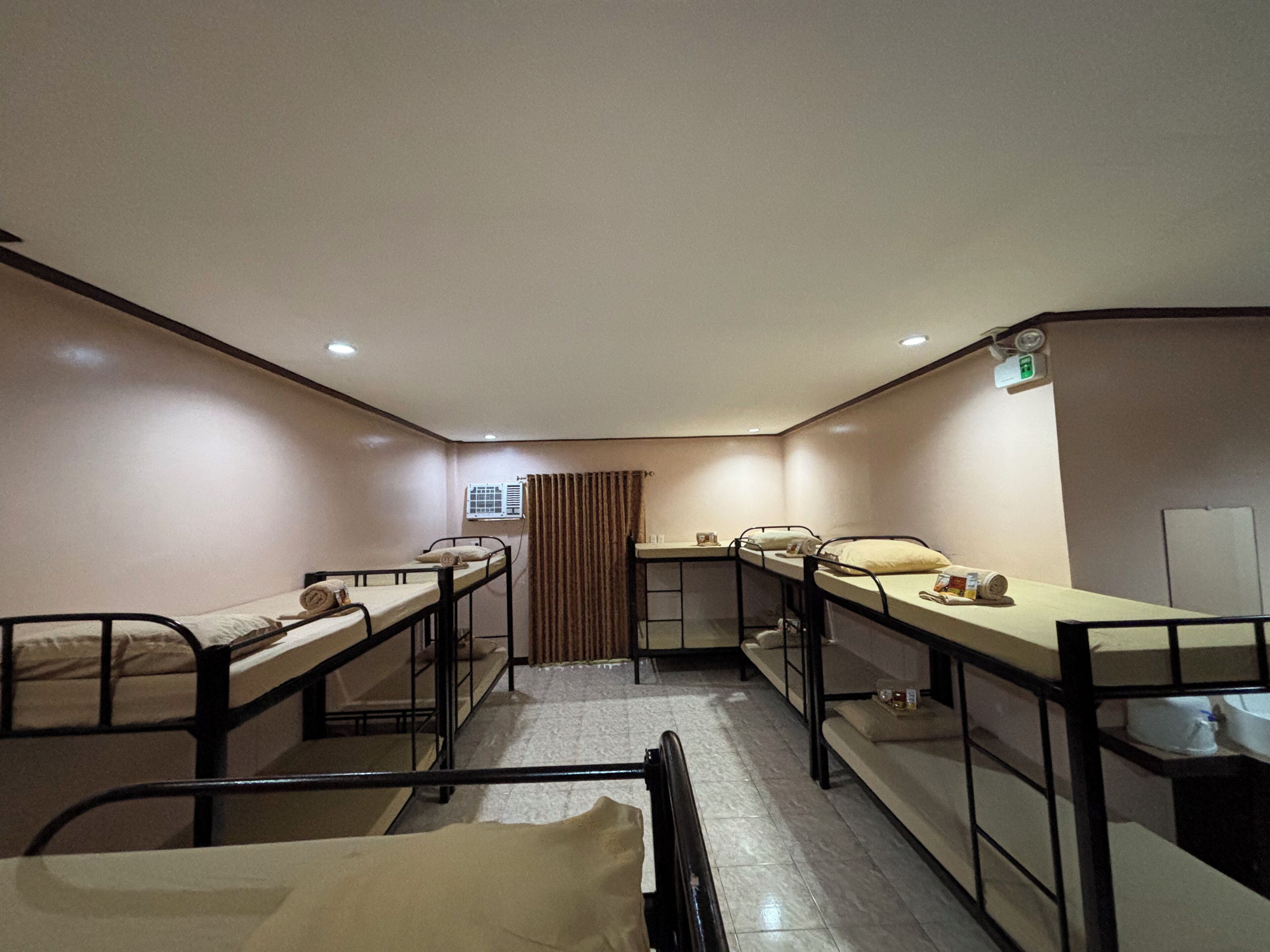 Un dormitorio con literas, una pequeña kitchenette y una ventana con cortinas.