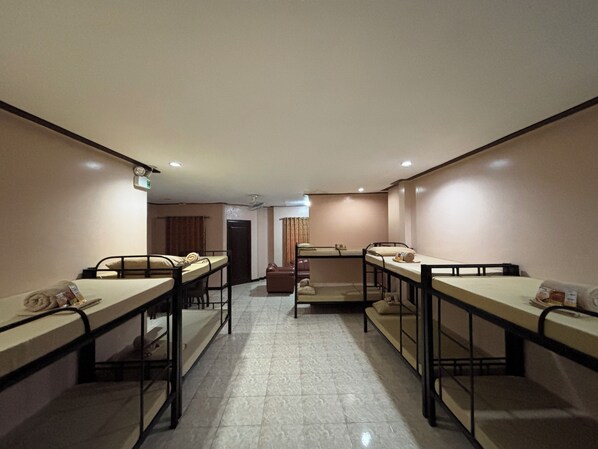 A hotel room with four single beds arranged in a row, a small seating area, and a door leading to another room. - D' Leonor Inland Resort And Adventure Park (Davao)