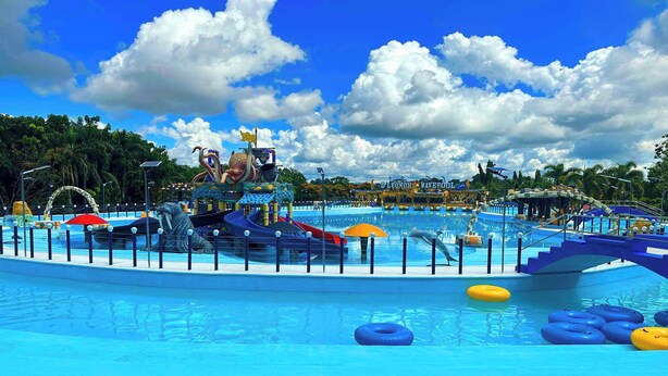 A water park with a large pool, slides, and inflatable rings. - D' Leonor Inland Resort And Adventure Park (Davao)