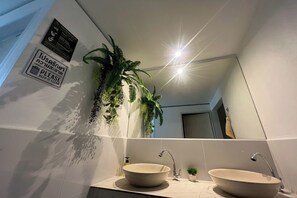 A bathroom with two sinks, a mirror, and a potted plant. - Lazy Lizard Hostel (Koh Samui)