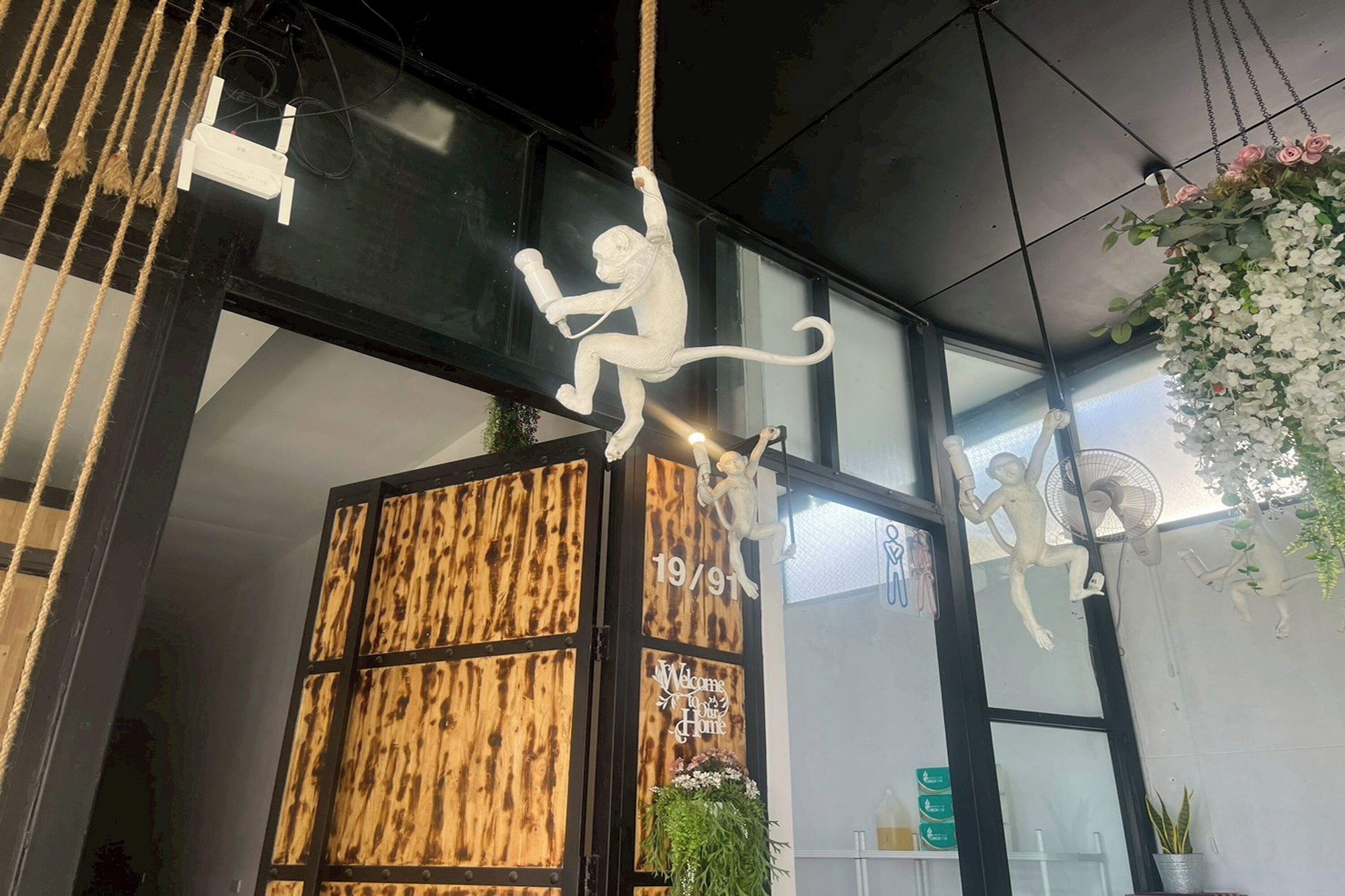 A modern interior with a wooden panel wall, a welcome sign, and monkey sculptures.