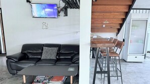Un espacio de sala moderno con un sofá de cuero negro, una mesita de centro pequeña y un televisor montado.