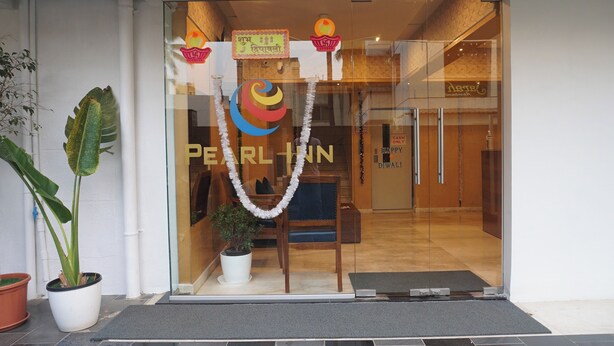 A hotel entrance with a glass door, a welcome mat, and a potted plant. - Executive Hotel Pearl Inn (Pune)
