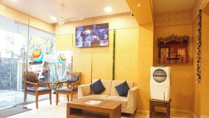 A hotel lobby with a sofa, chairs, a coffee table, a television, and a small shrine. - Executive Hotel Pearl Inn (Pune)