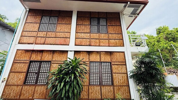 Un edificio de dos pisos con un diseño tradicional, con paneles de madera y ventanas de diseño a cuadrícula.
