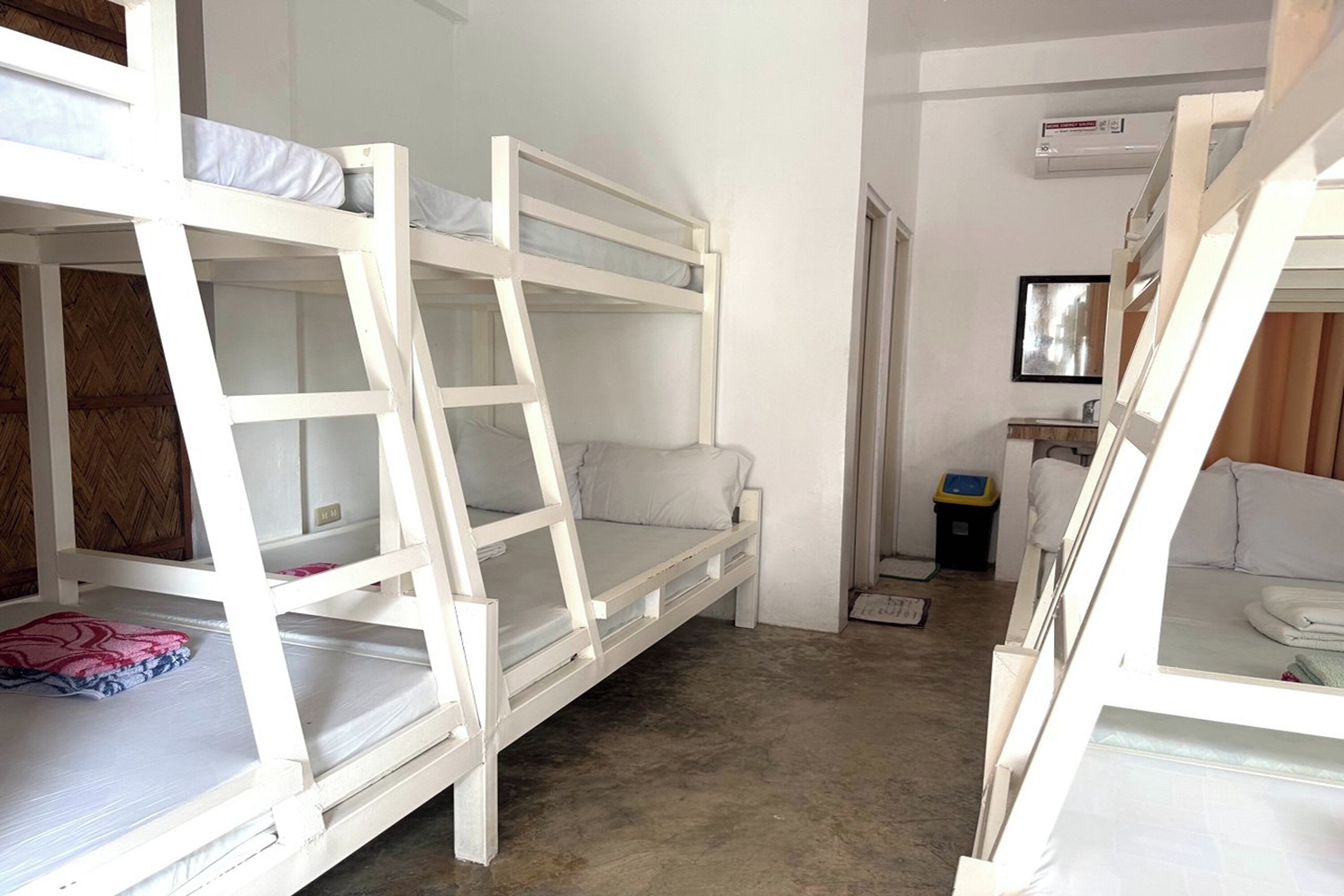 A room with bunk beds, a small desk, and a window.