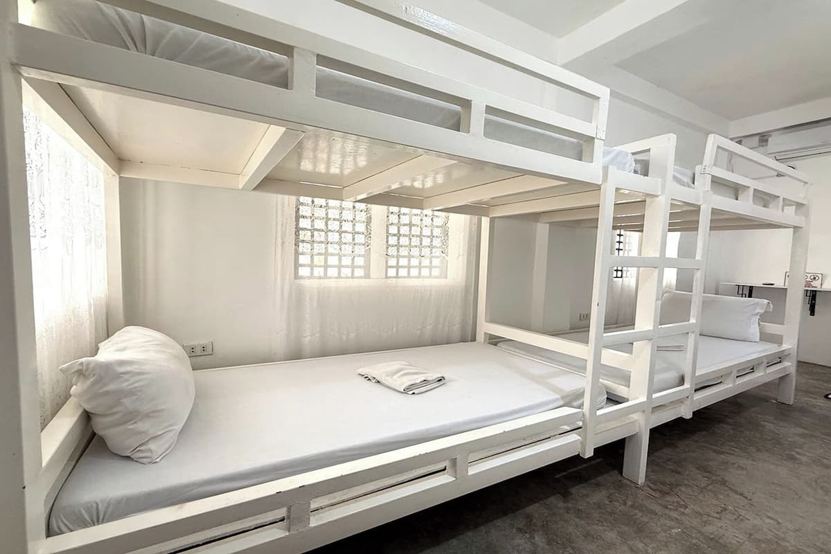 Habitación con literas, ventana, almohada blanca y toalla doblada en la litera inferior.