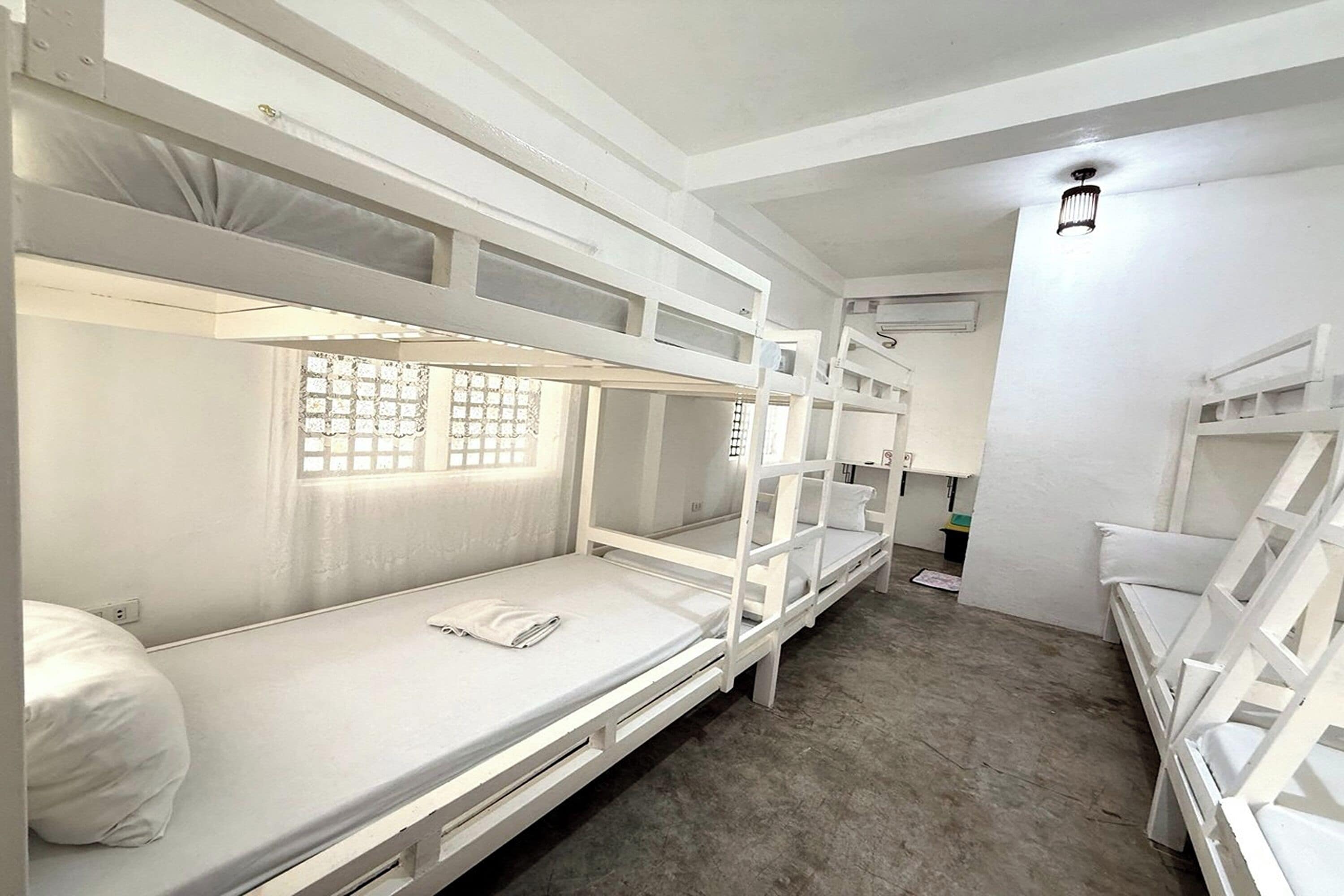 Habitación con literas, un escritorio y una lámpara, con ventana.
