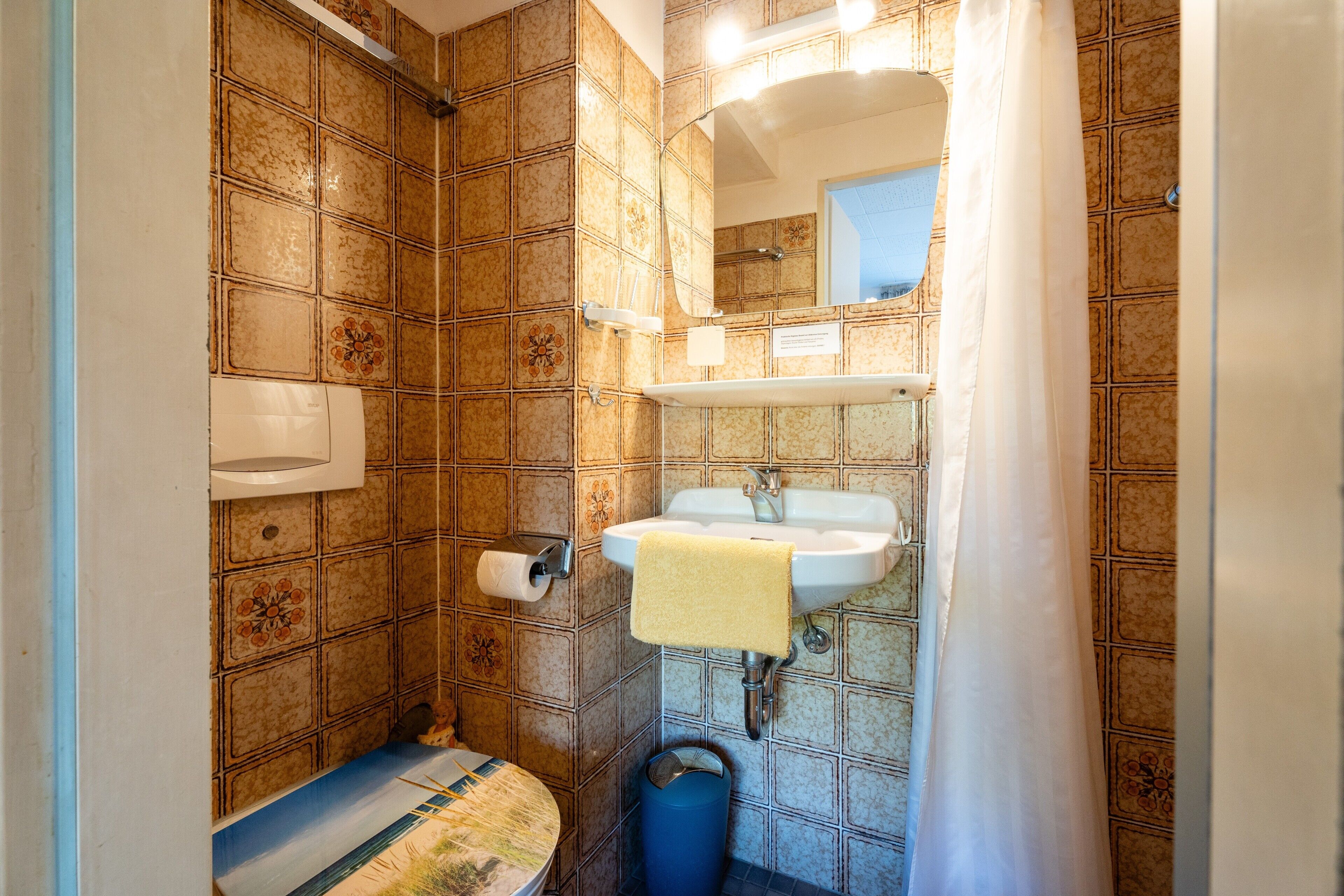 A bathroom with a toilet, sink, and shower curtain.