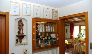 A room with a wooden cabinet displaying certificates, a statue, and various items. - Room 'Doppelzimmer Trimm Dich-stüble' with Shared Terrace, Shared Garden and Wi-Fi (Oberharmersbach)