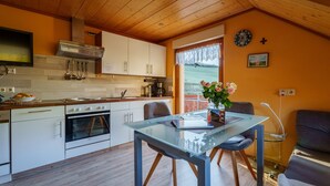 A modern kitchen with white cabinets, a built-in oven, and a dining area with a glass table and chairs. - Apartment 'Sonnenschein' with Shared Terrace, Garden and Wi-Fi (Oberharmersbach)