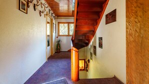 A hallway with a wooden staircase, a patterned carpet, and wall-mounted deer antlers. - Apartment 'Sonnenschein' with Shared Terrace, Garden and Wi-Fi (Oberharmersbach)