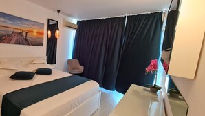 Ein ordentlich eingerichtetes Schlafzimmer mit einem großen Bett, Nachttischen, einem Schreibtisch und einem Sessel.