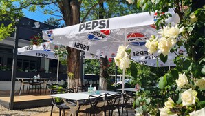 Ein Außenbereich mit Tischen und Stühlen unter Sonnenschirmen mit Pepsi-Logos.