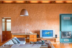A cozy living room with a large TV, wooden furniture, and a fireplace.