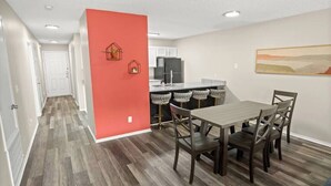 Une cuisine moderne avec des meubles blancs, un réfrigérateur noir et un plan de travail gris.