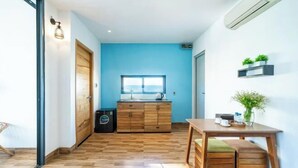 A modern kitchen with wooden cabinets, a window, and a built-in air conditioner. - Sea Vista Boutique Hotel & Apartment By Haviland (Da Nang)