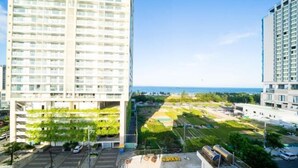 A high-rise building with multiple balconies and a view of a landscaped area with trees and a parking lot. - Sea Vista Boutique Hotel & Apartment By Haviland (Da Nang)