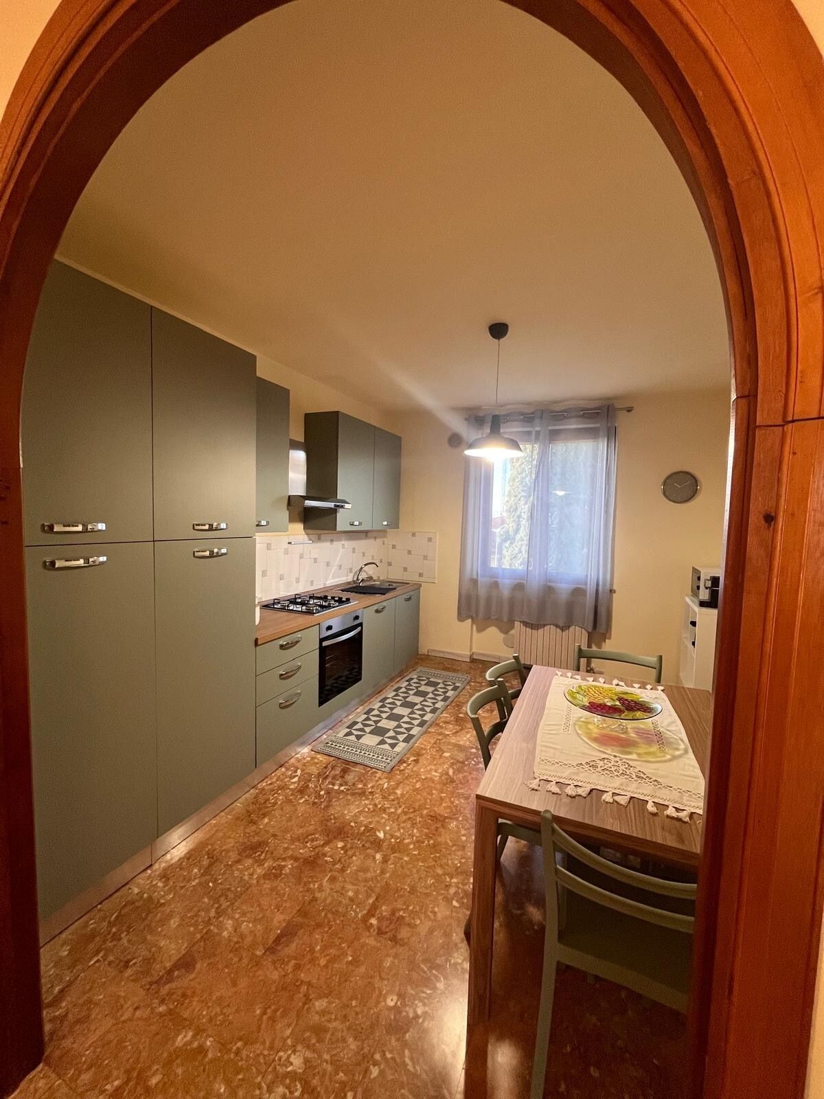 A kitchen with grey cabinets, a stove, and a dining table with a fruit platter.