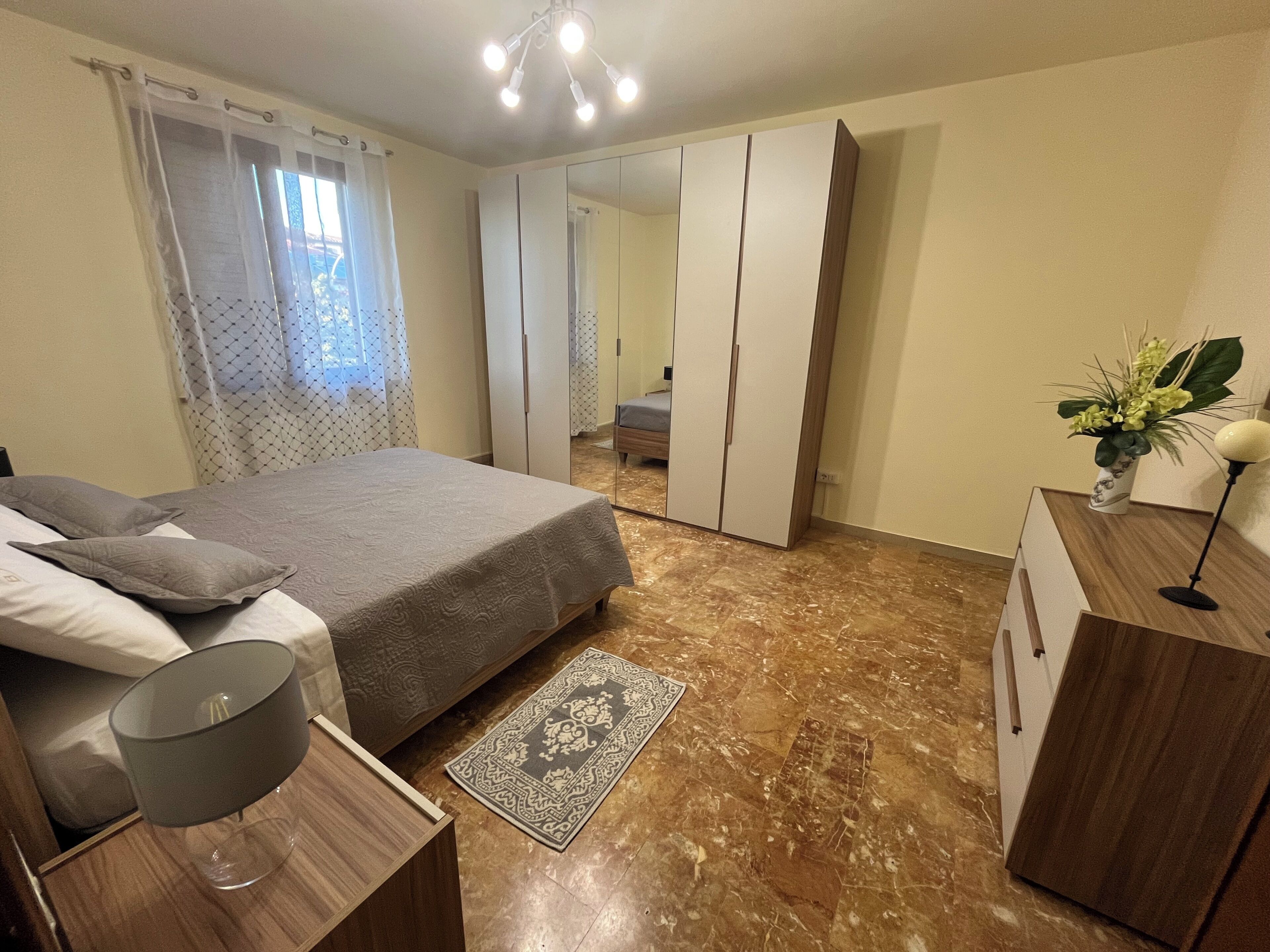Une chambre à coucher avec un lit, une table de chevet, une lampe et un miroir.