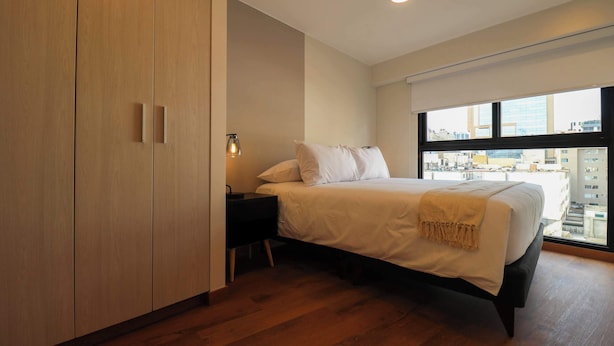 Ein modernes Schlafzimmer mit einem großen Bett, einem Nachttisch, einer Lampe und einem Kleiderschrank.