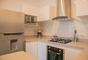 A modern kitchen with stainless steel appliances, a built-in microwave, a coffee maker, and a gas stove.