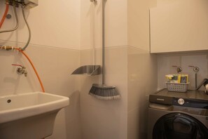 A bathroom with a sink, a shower, and a washing machine.