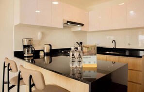 A modern kitchen with a central island, black countertop, stainless steel appliances, and wooden cabinets. - w* | Enchanting 1BR w/ Balcony in Barranco (Barranco)
