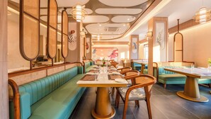 A restaurant with long green booths, wooden tables, and woven ceiling decorations.