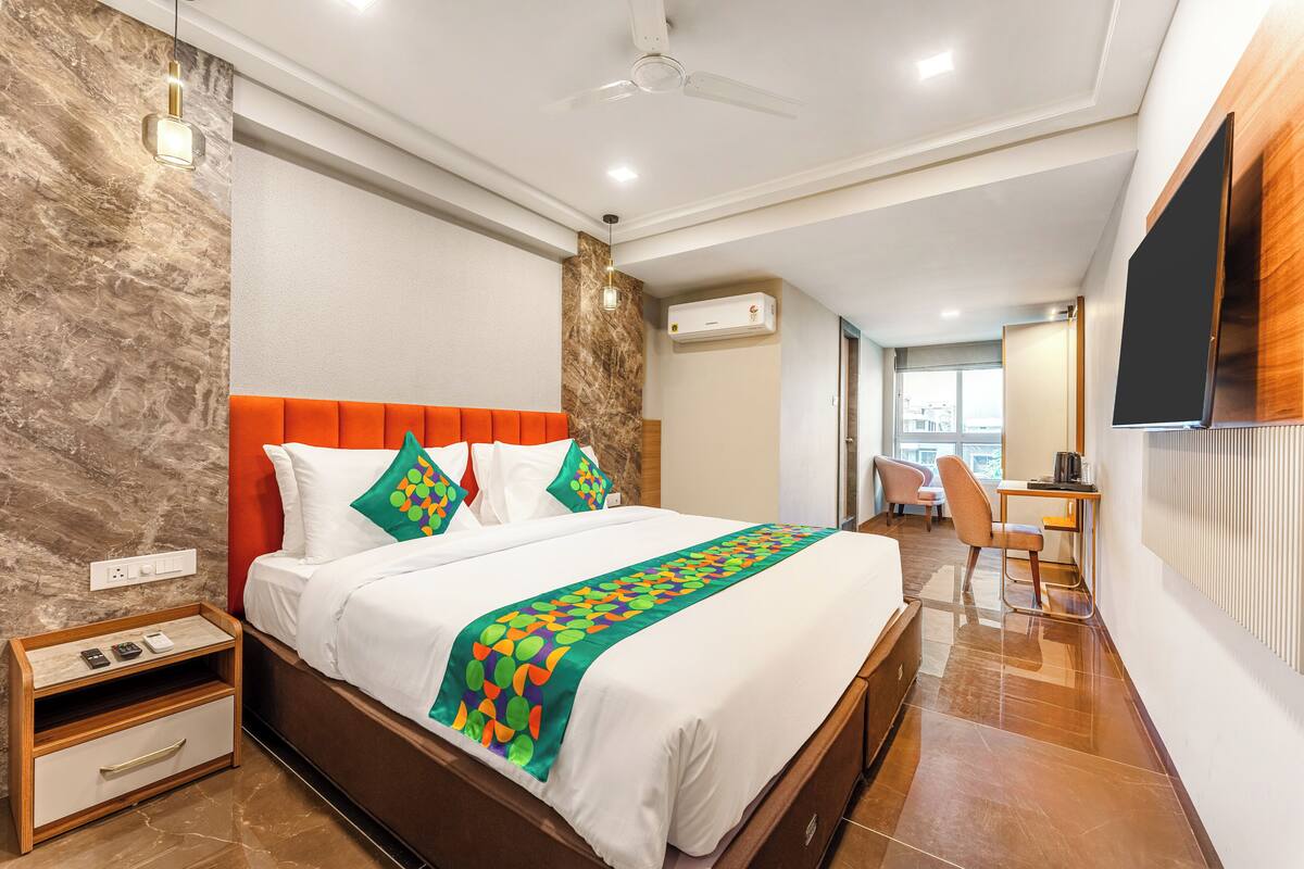A modern hotel room with a large bed, a desk, and a TV.