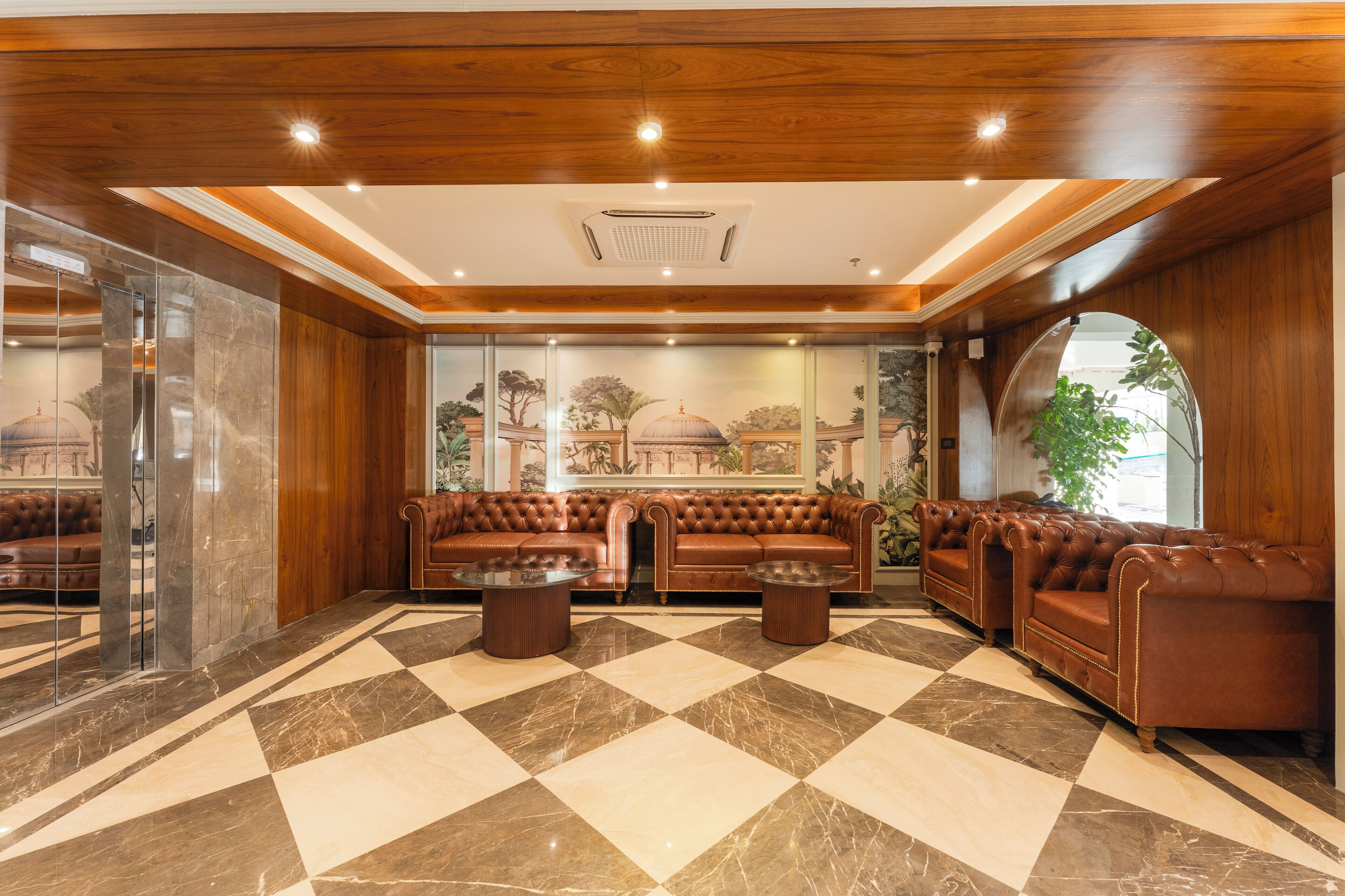A lobby with a checkered floor, leather sofas, and a glass elevator.
